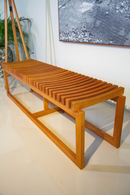 Banco Sucello com estrutura em madeira maciça de Jequitibá, 160 cm de largura, ideal para salas, varandas cobertas e espaços internos. Design minimalista e acabamento na cor Mel, perfeito para diversos estilos de decoração.