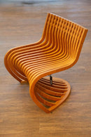 Poltrona Pantosh com design geométrico e escultural, inspirada na Cadeira Panton de Verner Panton e na Poltrona Willow de Charles Rennie Mackintosh. Estrutura em madeira maciça de alta qualidade, compensado multilaminado e acabamentos premium. Dimensões: 78 cm (A) x 66 cm (L) x 60 cm (P). Outros itens na fotografia não estão incluídos.