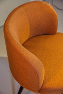 Poltrona Trila em tecido bouclé terracota, com estrutura de madeira maciça de eucalipto e acabamento em verniz PU. Ideal para compor ambientes sofisticados e versáteis. Dimensões: 84 cm (A) x 75 cm (L) x 72 cm (P). Outros itens na fotografia não estão incluídos.