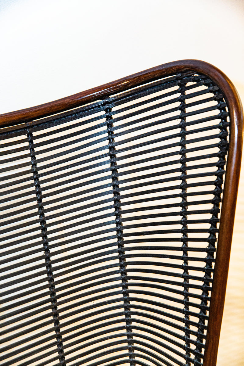 Sofá Manila feito à mão com estrutura em rattan natural, projetado para duas pessoas. Dimensões: 100 cm (A) x 120 cm (L) x 80 cm (P). Ideal para salas de estar, varandas ou áreas externas cobertas. Produto artesanal com variações de cor e textura. Outros itens na fotografia não estão incluídos.