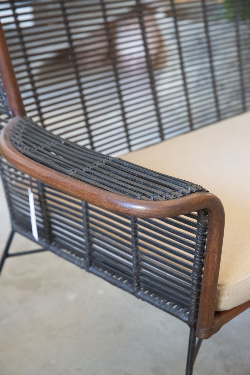 Sofá Manila feito à mão com estrutura em rattan natural, projetado para duas pessoas. Dimensões: 100 cm (A) x 120 cm (L) x 80 cm (P). Ideal para salas de estar, varandas ou áreas externas cobertas. Produto artesanal com variações de cor e textura. Outros itens na fotografia não estão incluídos.